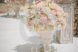 Beautiful bouquet of roses in a vase on a background of a wedding arch. Beautiful set up for the wedding ceremony