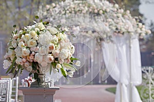 Beautiful bouquet of roses in a vase on a background of a wedding arch. Beautiful set up for the wedding ceremony.