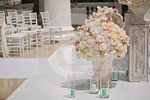 Beautiful bouquet of roses in a vase on a background of a wedding arch. Beautiful set up for the wedding ceremony.