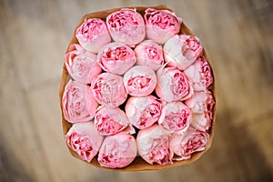 Beautiful bouquet of rosy peonies wrapped in craft paper