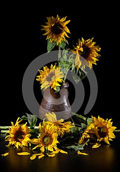 Beautiful bouquet of sunflowers in vase on a black table over black background