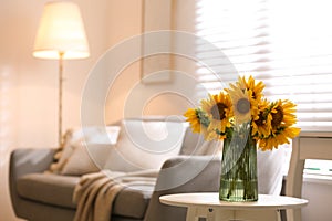 Beautiful bouquet of sunflowers in vase on white table indoors. Space for text