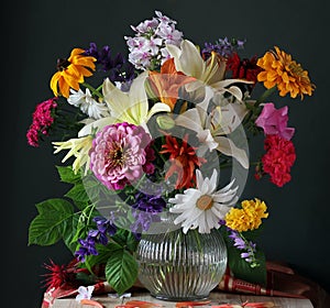 Beautiful bouquet of various garden flowers in glass jug.