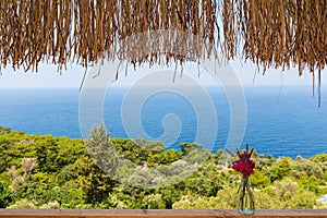 Beautiful bouquet in vase on wooden hand rail against seascape background