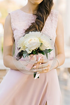 Beautiful bouquet of white roses in the hands of a girl in a pink dress