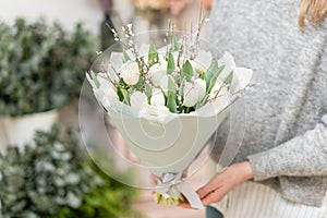 Beautiful bouquet of white tulips flowers in woman hand. the work of the florist at a flower shop. cute lovely girl