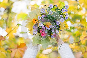 Beautiful bouquet of wild flowers in woman`s hands on colorful autumn background. Bright nature colors