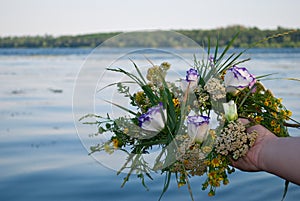 Beautiful bouquet of a wreath of wildflowers a girl holding a river over water