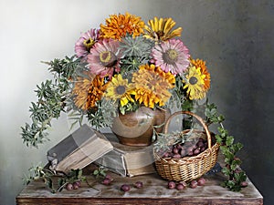 A beautiful bouquet of zinnias in a vase with water and gooseberry berries in a basket