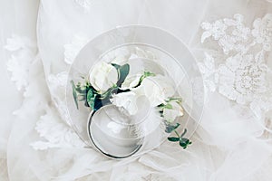 Beautiful boutonniere with ring on white wedding dress, closeup