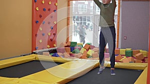 Beautiful boy blond jumps on a trampoline in a children's playroom