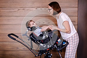 Beautiful boy child in a special wheelchair. Toddler with cerebral palsy