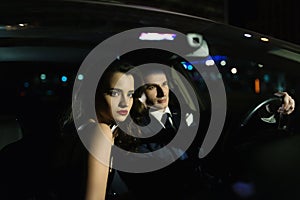 Beautiful boy and girl sitting in the car, the reflection of the street in the glass of the car. Love story