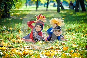 Beautiful boy, little child laying with a lot of yellow autumn leaves in park. Kid boy having fun on sunny warm october day.