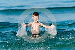 Beautiful boy making splashes in the middle of sea waves