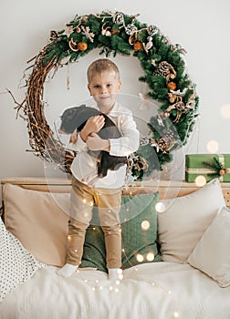 Beautiful boy near a Christmas tree with gifts feeding