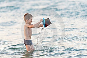 Beautiful boy playing with a bucket toy in the sea