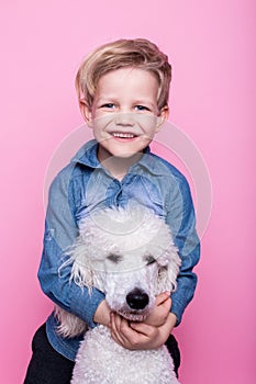 Beautiful boy with Royal Standard Poodle. Studio portrait over pink background. Concept: friendship between boy and his dog