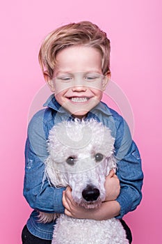 Beautiful boy with Royal Standard Poodle. Studio portrait over pink background. Concept: friendship between boy and his dog