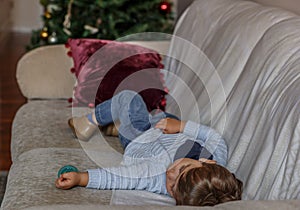 Beautiful boy is sleeping peacefully on the sofa in the living room of his house