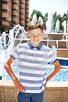 a beautiful boy on vacation in the summer in the city near the fountain