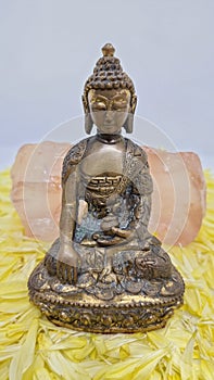 Beautiful brass Buddha statue sitting on a bed of flower petals