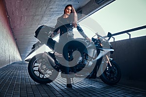 Beautiful brave woman is leaning on her motobike in tunnel