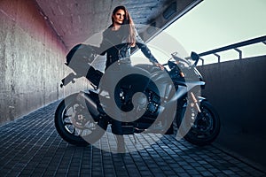 Beautiful brave woman is leaning on her motobike in tunnel photo