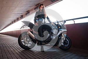 Beautiful brave woman is leaning on her motobike in tunnel photo