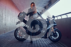 Beautiful brave woman is leaning on her motobike in tunnel photo