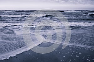 Beautiful breaking waves on sandy beach on atlantic ocean in black and white, hendaye, basque country,