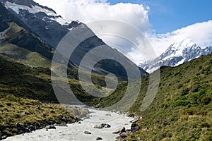 A beautiful breathtaking scene of a massive mountain with a small fresh river melting from glacier near the trekking route at