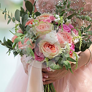 Beautiful bridal bouquet in hands of the bride. Wedding bouquet of peach roses by David Austin, single-head pink rose aqua,
