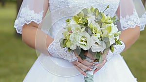 Beautiful bridal bouquet in hands of young bride dressed in white wedding dress