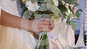 Beautiful bridal bouquet in hands of young bride dressed in white wedding dress. Close up of big bunch of fresh white