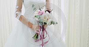 Beautiful bridal bouquet in hands of young bride dressed in white wedding dress. Close up of big bunch of fresh white
