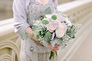 Beautiful bridal bouquet made of creamy and light pink peonies, roses, ranunculuses, baby breath and eucalyptus branches