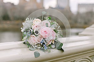 Beautiful bridal bouquet made of creamy and light pink peonies, roses, ranunculuses, baby breath and eucalyptus branches