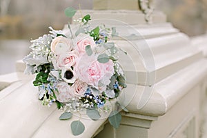 Beautiful bridal bouquet made of creamy and light pink peonies, roses, ranunculuses, baby breath and eucalyptus branches