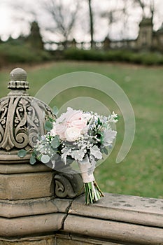 Beautiful bridal bouquet made of creamy and light pink peonies, roses, ranunculuses, baby breath and eucalyptus branches