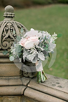 Beautiful bridal bouquet made of creamy and light pink peonies, roses, ranunculuses, baby breath and eucalyptus branches