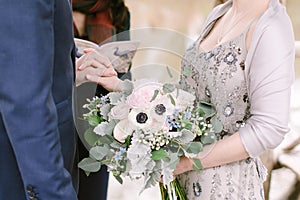 Beautiful bridal bouquet made of creamy and light pink peonies, roses, ranunculuses, baby breath and eucalyptus branches