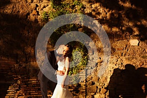 Beautiful bridal couple embracing and kissing at sunset