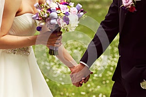 Beautiful bridal couple having fun in the park on their wedding day flower bouquet