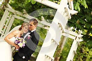 Beautiful bridal couple having fun in the park on their wedding day flower bouquet