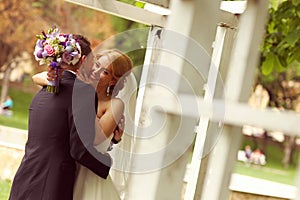 Beautiful bridal couple having fun in the park on their wedding day flower bouquet