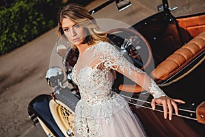 Beautiful bride with attitude leaning on a classic car