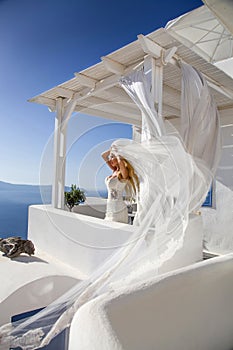 Beautiful bride blonde female model in amazing wedding dress poses on the island of Santorini