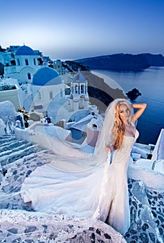 Beautiful bride blonde female model in amazing wedding dress poses on the island of Santorini