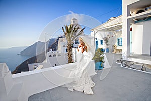 Beautiful bride blonde female model in amazing wedding dress poses on the island of Santorini